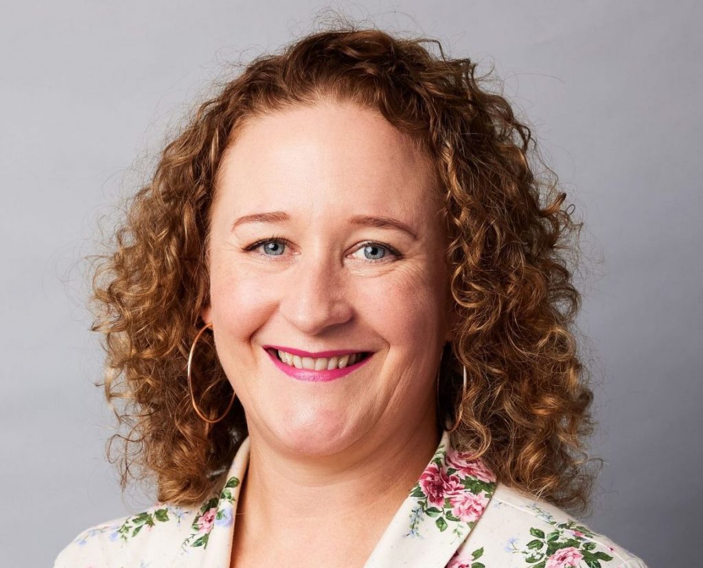 Photo of Dr Erica McIntyre. She is smiling and has curly light brown shoulder length hair.