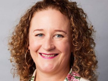 Photo of Dr Erica McIntyre. She is smiling and has curly light brown shoulder length hair.