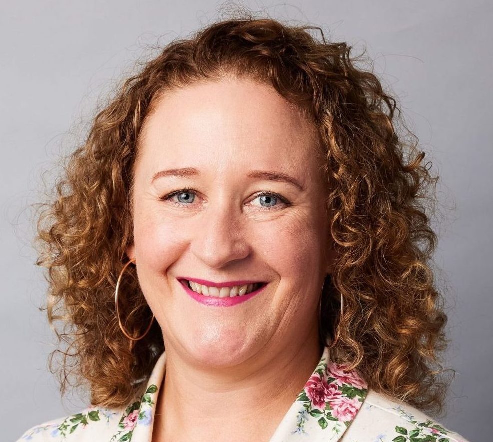 Photo of Dr Erica McIntyre. She is smiling and has curly light brown shoulder length hair.